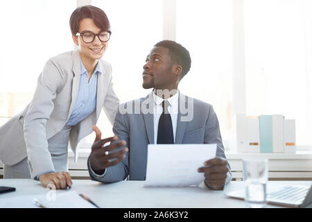 Porträt der jungen Afrikaner Unternehmer sitzen am Schreibtisch im Büro und im Gespräch mit weiblichen Kollegen, während Sie Dokumente, kopieren Raum Stockfoto