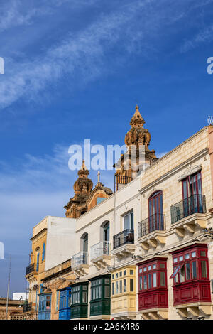 Zu den traditionellen maltesischen Häuser mit Balkonen in Msida, Malta, oben in der St. Joseph Kirche Türme im Hintergrund. Stockfoto