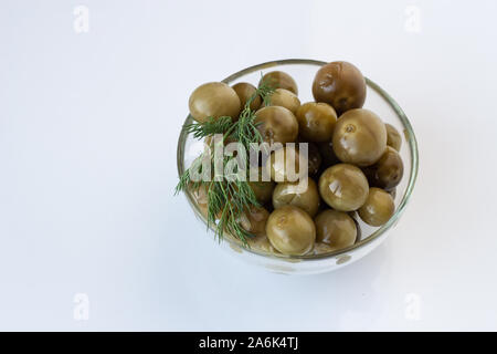 Fermentierten grünen Tomaten mit Dill in eine Glasplatte auf weißem Hintergrund Stockfoto