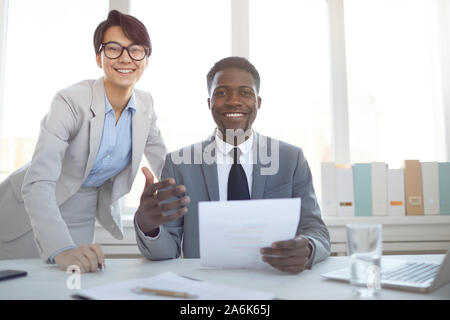 Portrait von lächelnden Afro-amerikanische Unternehmer sitzen am Schreibtisch im Büro und suchen an der Kamera, während mit Kollegin Posing, kopieren Raum Stockfoto