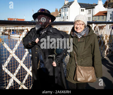 Eine Frau links Waffen mit einem Goth, da Sie die Whitby Goth Wochenende in Whitby, Yorkshire, wie Hunderte von Goten steigen auf die Stadt am Meer, wo Bram Stoker gefunden Inspiration für 'Dracula-' nach dem Aufenthalt in der Stadt im Jahre 1890. PA-Foto. Bild Datum: Sonntag, 27. Oktober 2019. Die Whitby Goth Wochenende ist zweimal im Jahr eine alternative Music Festival von Jo Hampshire organisiert, bestehend aus zwei Nächte von Live Bands an den Veranstaltungsorten in der Stadt. Die Ursprünge des Festivals werden in einer Sitzung von rund vierzig von Pen die Ms-Hampshire-Pals im Jahr 1994. Die Veranstaltung hat sich zu einem der weltweit beliebtesten Goth werden Stockfoto