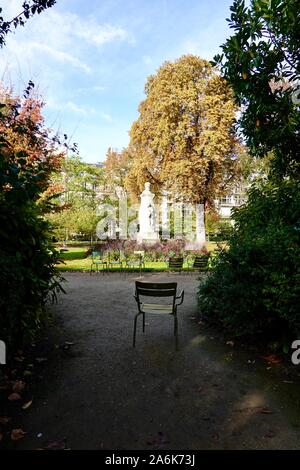 Grüne Stühle, die um einen sonnigen Lage, mit einem Stuhl in den Schatten. Herbst in den Luxemburg Gärten, Oktober in Paris, Frankreich Stockfoto