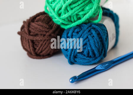 Close up of delicate multi colored woollen yarns displayed on white background with needleColorful threads of wool Stockfoto
