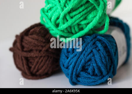 Close up of delicate multi colored woollen yarns displayed on white background with needleColorful threads of wool Stockfoto