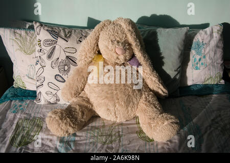 Riesige creme Teddybär stützte sich auf einem Bett. Stockfoto