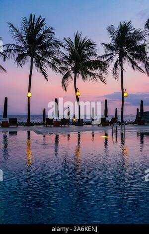 Luxus hotel Swimmingpool mit Palmen und den Indischen Ozean in der Dämmerung, Candidasa, Bali, Bali, Indonesien, Südostasien, Asien Stockfoto