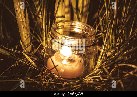 Kerze im Glas Glas im Gras. Nacht das Leben der Pflanzen im Garten Stockfoto