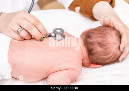 Kinderarzt untersucht zwei Wochen altes Baby zurück in der Kinderklinik. Arzt mit einem Stethoskop Herz und Lungen zu überprüfen. Neugeborene Check-up Konzept Stockfoto