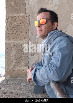 Nachdenklicher Mann mit Sonnenbrille stützte sich auf eine historische Fenster nach draußen Stockfoto