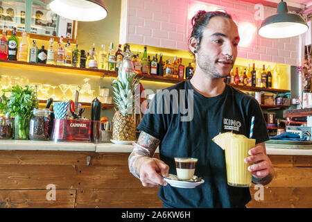 Barcelona Spanien,Catalonia Ciutat Vella,El Raval,Kino Cafe,Restaurant,Bar,Dining,Mann,Kellner,mit Getränken,Kaffee,Smoothie,Nase Piercing,nostr Stockfoto