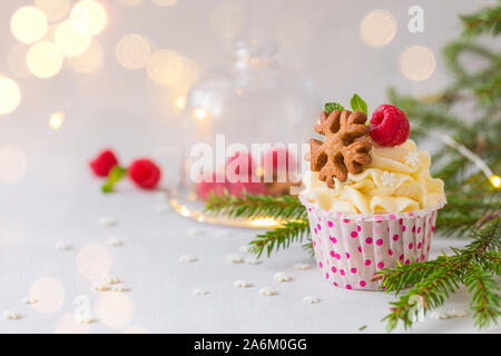 Weihnachten kleine Kuchen oder Muffins mit Sahne und Himbeere, über die Fir Tree Branches Hintergrund, getönt Stockfoto