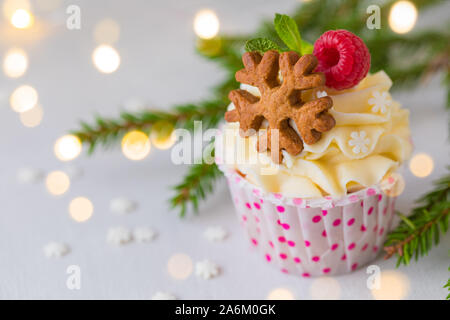 Weihnachten kleine Kuchen oder Muffins mit Sahne und Himbeere, über die Fir Tree Branches Hintergrund, getönt Stockfoto