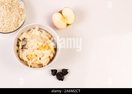 Salat von Apple, Orange, oat Hopfen und Pflaumen mit Honig in eine weiße Platte auf einem weißen Hintergrund. Stockfoto