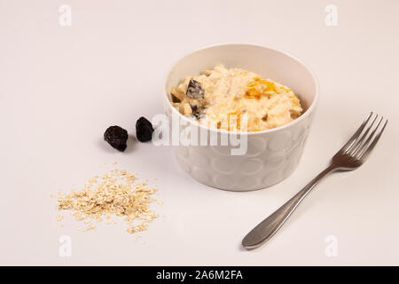 Salat von Apple, Orange, oat Hopfen und Pflaumen mit Honig in eine weiße Platte auf einem weißen Hintergrund. Stockfoto