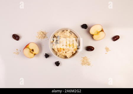 Salat von Apple, Orange, oat Hopfen und Pflaumen mit Honig in eine weiße Platte auf einem weißen Hintergrund. Stockfoto