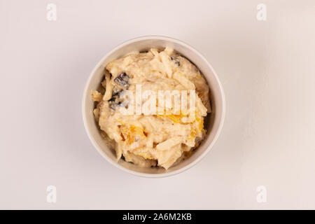 Salat von Apple, Orange, oat Hopfen und Pflaumen mit Honig in eine weiße Platte auf einem weißen Hintergrund. Stockfoto