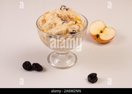 Salat von Apple, Orange, oat Hopfen und Pflaumen mit Honig in einem Glas Platte auf einem weißen Hintergrund. Stockfoto