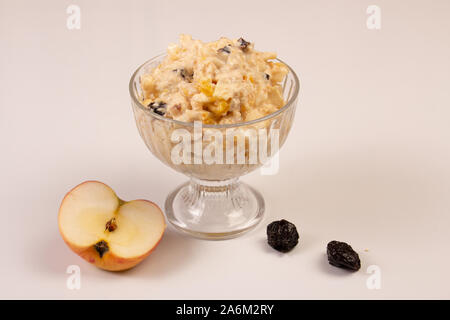 Salat von Apple, Orange, oat Hopfen und Pflaumen mit Honig in einem Glas Platte auf einem weißen Hintergrund. Stockfoto