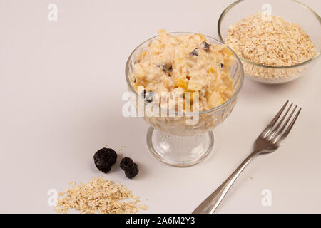 Salat von Apple, Orange, oat Hopfen und Pflaumen mit Honig in eine weiße Platte auf einem weißen Hintergrund. Stockfoto