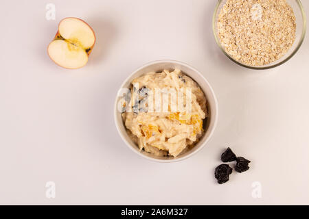 Salat von Apple, Orange, oat Hopfen und Pflaumen mit Honig in eine weiße Platte auf einem weißen Hintergrund. Stockfoto