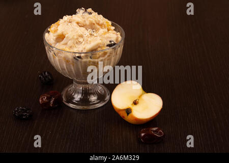 Salat von Apple, Orange, oat Hopfen und Pflaumen mit Honig in einem Glas Platte auf braunem Grund. Stockfoto