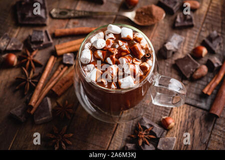 Heiße Schokolade mit Marshmallows und Schokolade Sirup in ein Glas Schale. Leckere süße Getränke. Holz- Hintergrund Stockfoto