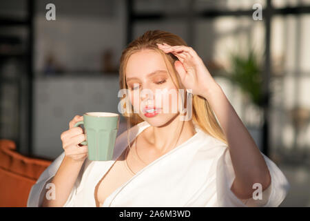 Blond ansprechende Frau genießt sonnigen Morgen und Kaffee Stockfoto