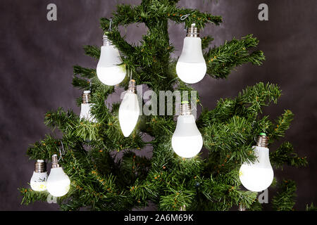 Der Weihnachtsbaum ist mit elektrischen Lampen in Matt-weißes LED eingerichtet. Energiesparende und energieeffiziente Beleuchtung, kreative Idee für Stockfoto