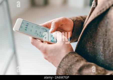 Die Hände der Jungen elegante Ökonom Scrollen durch finanzielle Daten in Smartphone Stockfoto
