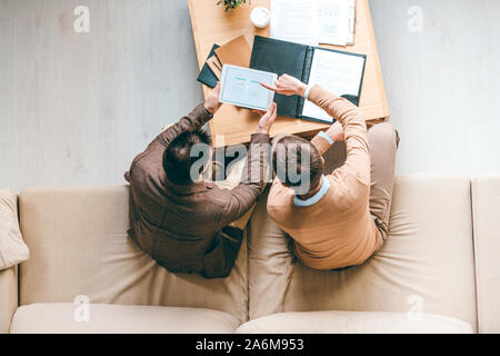 Junge Designer von Arbeitsplatz sitzen und einige Ideen von neuer Software diskutieren Stockfoto