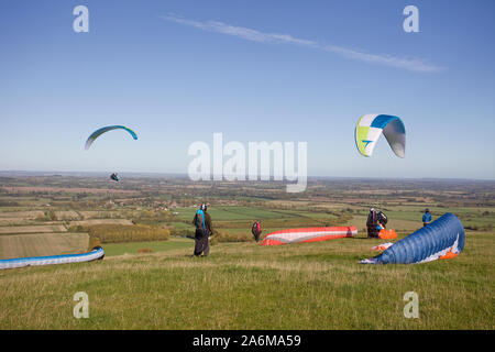 Gleitschirme, die von den Hügeln von Uffington White Horse Hill in Oxfordshire, England Stockfoto