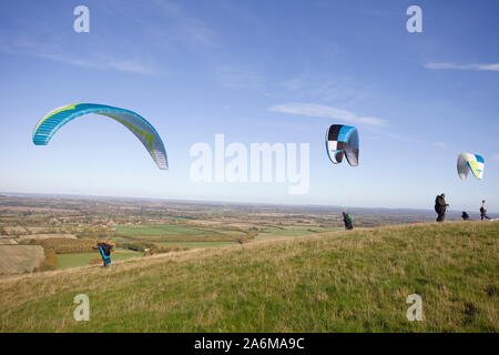 Gleitschirme, die von der Oberseite des Uffington White Horse Hill in Oxfordshire, England Stockfoto