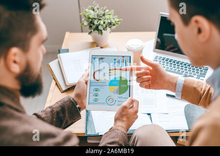 Einer der jungen zeitgenössischen Ökonomen der Diagramm zeigt auf dem Touchpad angezeigt Stockfoto