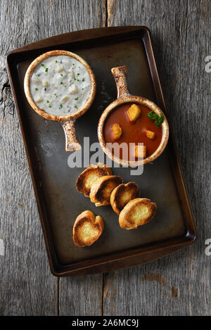 Zwei frische, hausgemachte Schalen von Clam Chowder und Tomatensuppe mit Knoblauch Toast auf einem Backblech. Stockfoto