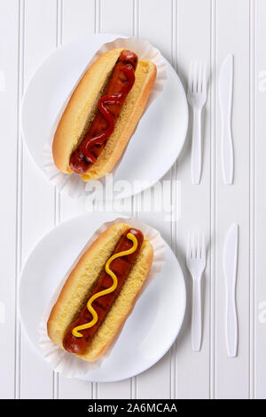 Blick von oben auf ein komplett weißes Ort Einstellung mit Hot Dogs mit Ketchup, eine mit Senf. Stockfoto