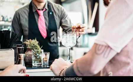 Barkeeper Vorbereitung Gin Tonic Cocktail - die Leute Spaß haben in der amerikanischen Bar warten auf Barkeeper Getränke Stockfoto