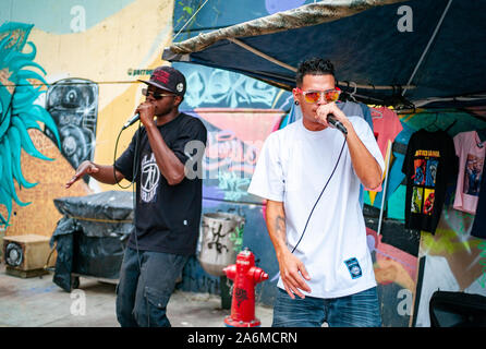 Medellin, Antioquia/Kolumbien - 28. Februar 2019: Zwei Rapper Männer singen mit Mikrofonen und den Verkauf von T-Shirts in der Comuna 13, Touristische künstlerische Urb. Stockfoto
