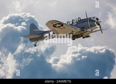 Ein aus der Zeit des Zweiten Weltkriegs Douglas SBD Dauntless dive Bomber durch dramatische Wolken fliegen. Stockfoto