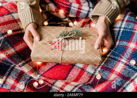 Die Hände der jungen Frau mit verpackt Geschenkverpackung mit roter Stern und Nadelbaum auf der Oberseite Stockfoto