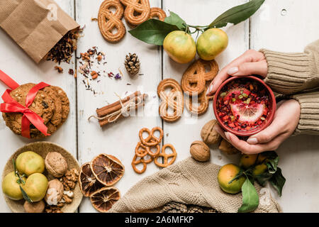 Blick auf weibliche Hände, die Becher mit heißem Getränk mit Weihnachten Essen rund um Stockfoto
