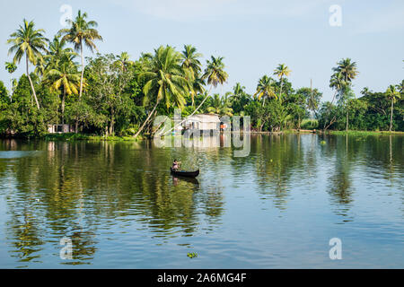 Alappuzha, Indien - 15. November 2017: Lokale indische Mann in kleinen Boot über den Fluss in die Kerala backwaters von tropischen Wald gesäumt Stockfoto