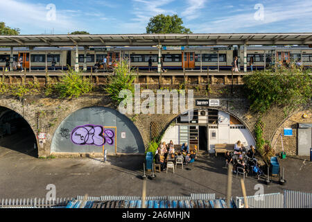 Menschen sitzen außerhalb der Bar Story Bar in einem Eisenbahn arch unter Peckham Rye Bahnhof. Stockfoto