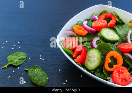 Gesunde Gemüse Salat von frischen Tomaten, Gurken, Zwiebeln, Spinat, Paprika und Sesam. Stockfoto