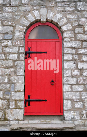 Die leuchtend rote Tür mit schwarzem Eisen Hardware ist der Eingang zum alten Stein Gibraltor Point Lighthouse auf Toronto Island. Stockfoto