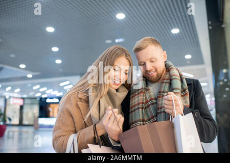 Glückliche junge Käufer, die bei einer von präsentiert in paperbag nach dem Einkaufen Stockfoto