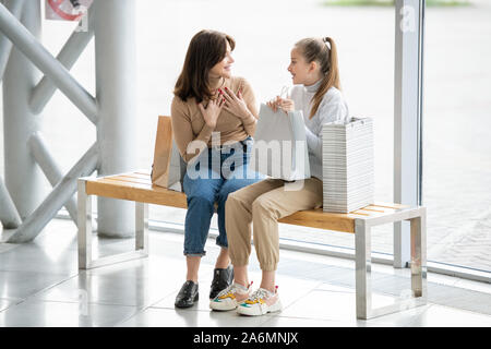 Freundliche Frauen in casualwear diskutieren etwas neugierig, während mit Rest Stockfoto