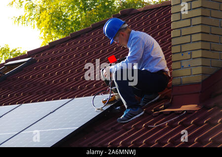 Montage, Installation und Überprüfung der Solaranlage auf dem Hausdach durch Techniker. Mann während der Inspektion der erneuerbaren Strom Generator. Stockfoto