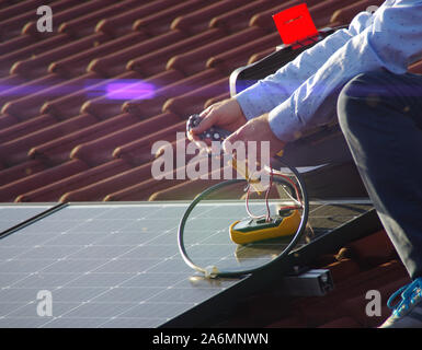 Montage, Installation und Überprüfung der Solaranlage auf dem Hausdach durch Techniker. Mann während der Inspektion der erneuerbaren Strom Generator. Stockfoto