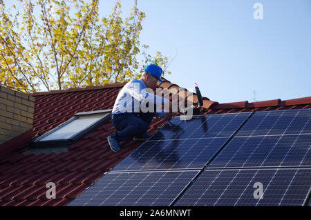 Montage, Installation und Überprüfung der Solaranlage auf dem Hausdach durch Techniker. Mann während der Inspektion der erneuerbaren Strom Generator. Stockfoto