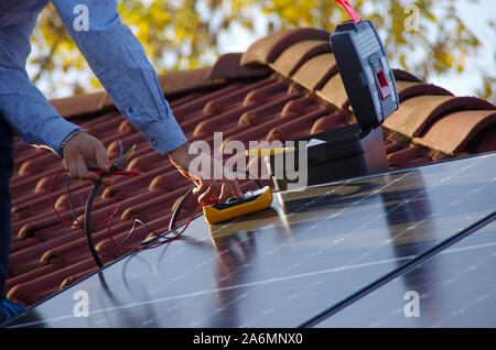 Montage, Installation und Überprüfung der Solaranlage auf dem Hausdach durch Techniker. Mann während der Inspektion der erneuerbaren Strom Generator. Stockfoto